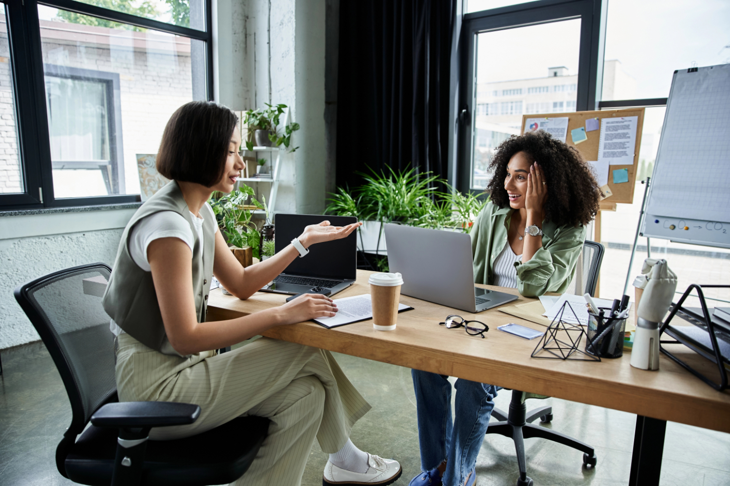 two women speaking over a desk at a laptop