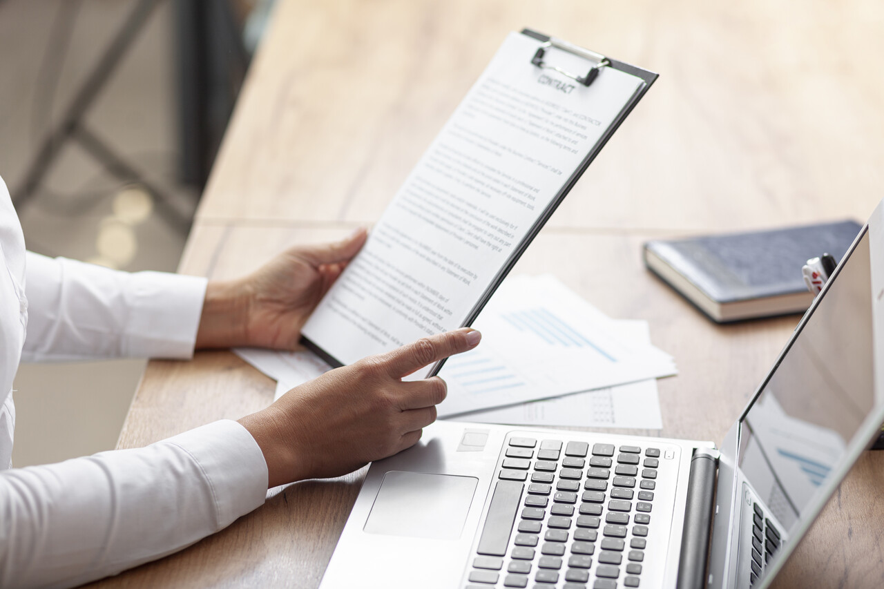 Why Every Role Needs a Job Description - Featured Image (Person holding a clipboard next to a laptop)